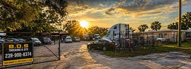 Trucks and trailers at the B.O.S. Trucking & Site yard in Fort Myers at sunset